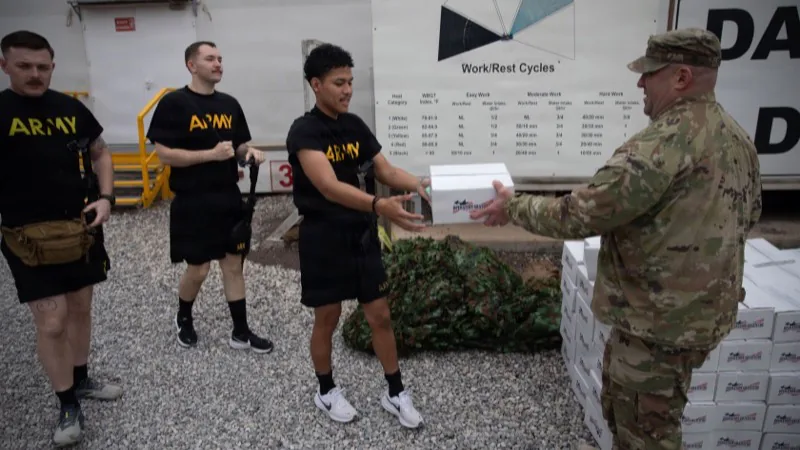 A sergeant major hands a care package to a fellow soldier